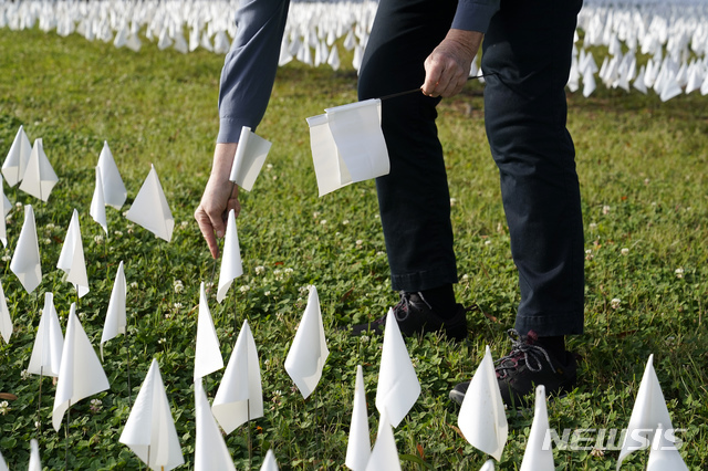 [워싱턴=AP/뉴시스]27일(현지시간) 미 워싱턴 DC의 로버트 F 케네디 메모리얼 경기장 근처에서 한 자원봉사자가 코로나19로 사망한 미국인들을 추모하는 흰 깃발을 꽂고 있다. 2020.10.28.