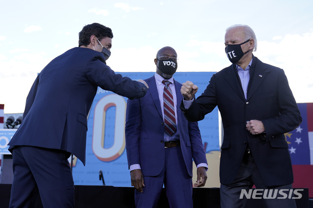 [애틀랜타=AP/뉴시스] 조 바이든 미국 대통령 당선인이 4일(현지시간) 조지아 연방 상원의원 민주당 후보인 래피얼 워녹(왼쪽) 및 존 오소프(가운데)와 무대에서 팔꿈치 인사를 나누고 있다. 2021.1.5.