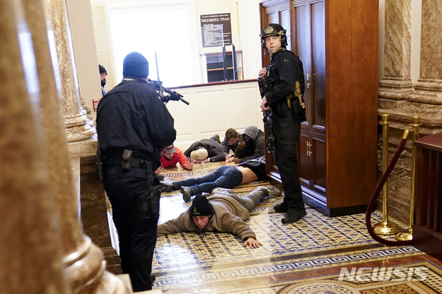 [워싱턴=AP/뉴시스]6일(현지시간) 미 의회 경비대가 의사당에 난입한 도널드 트럼프 대통령 지지자들을 하원 근처에서 총으로 제압하고 있다.