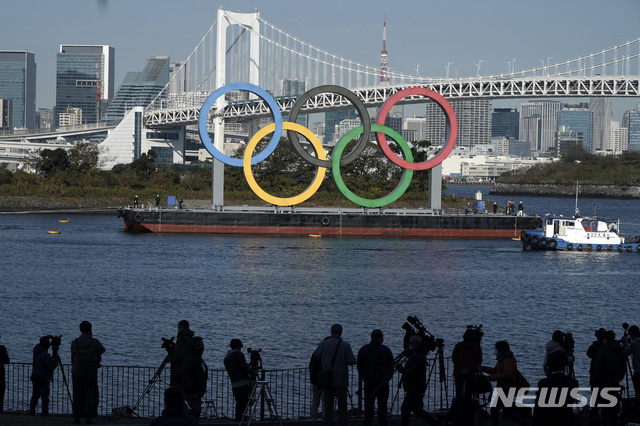 [도쿄=AP/뉴시스] 작년 12월 일본 도쿄 오다이바 해상공원에 올림픽 상징인 오륜 조형물을 사람들이 구경하고 있다. 지난 8월 철거됐던 조형물은 4개월 만에 다시 설치됐다. 2021.01.08.