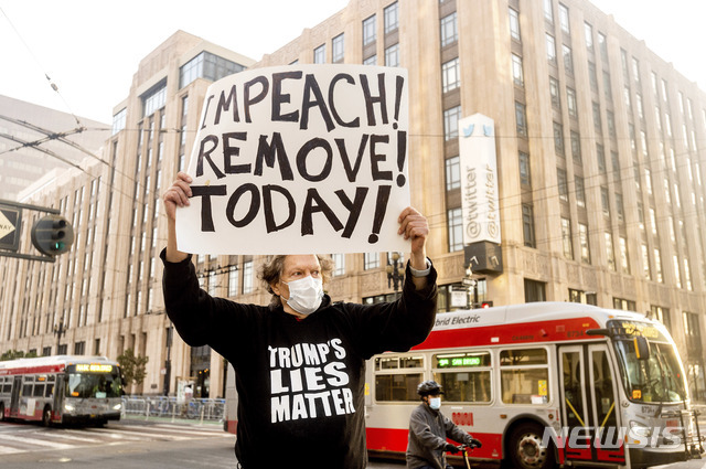 [샌프란시스코=AP/뉴시스]11일(현지시간) 미 캘리포니아주 샌프란시스코 트위터 본사 앞에서 한 시민이 도널드 트럼프 대통령의 탄핵을 촉구하는 손팻말을 들고 1인 시위를 벌이고 있다. 이날 경찰은 보수단체 시위에 대비해 울타리를 치고 시위에 대비했다.