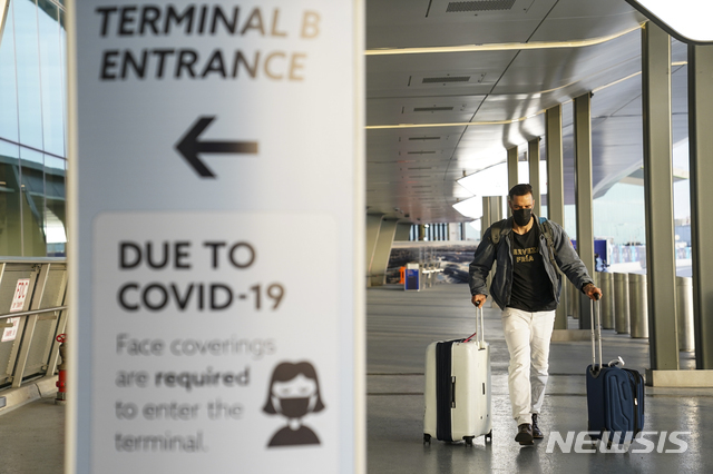 [뉴욕=AP/뉴시스] 25일(현지시간) 미국 뉴욕 라과디아공항에서 한 승객이 걷고 있는 가운데 신종 코로나바이러스 감염증(코로나19) 관련 안내문이 보인다. 2020.11.26.