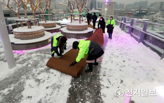 [천지일보=남승우 기자] 눈이 내린 12일 오후 서울 중구 서울로7017에서 관계자들이 미끄럼 방지를 위해 야자매트를 깔고 있다. ⓒ천지일보 2021.1.12