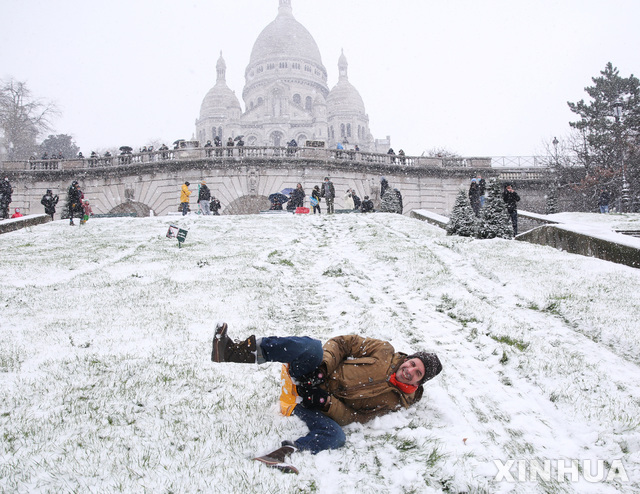 16일(현지시간) 프랑스 파리의 눈 덮인 몽마르트르 언덕에서 한 시민이 장바구니를 타고 눈썰매를 즐기고 있다. (출처: 뉴시스)