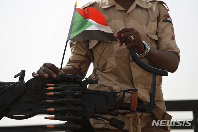 수단의 이스트 나일 주에 파견된 수단군 작전지원부대의 한 병사가  2019년 6월의 사열식에서 국기를 들어보이고 있다. (출처: 하르툼(수단)=AP/뉴시스)