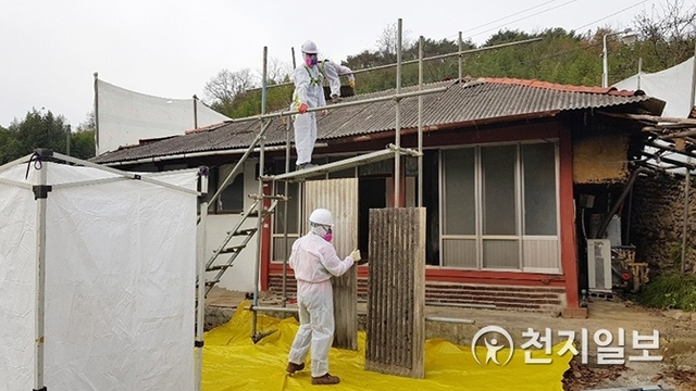 1급 발암물질 ‘석면’을 함유한 슬레이트 지붕을 작업자들이 방독면을 쓰고 철거하고 있다.  (제공: 진주시) ⓒ천지일보 2018.12.20