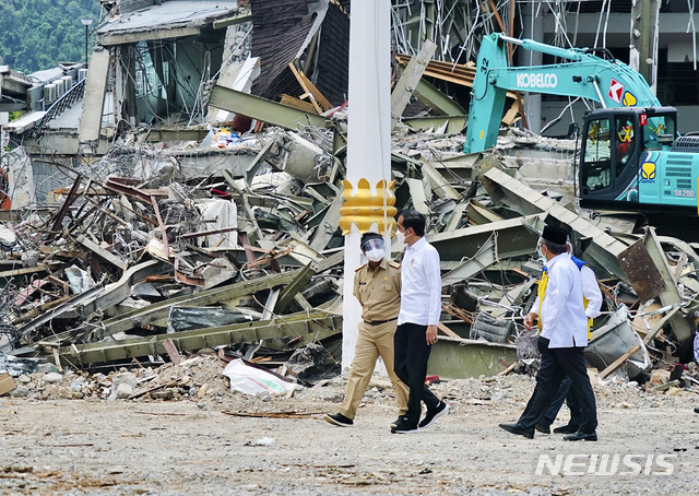 [마무주=AP/뉴시스]인도네시아 대통령궁이 공개한 사진에 조코 위도도(가운데) 대통령이 19일 인도네시아 웨스트 술라웨시주 마무주 지진으로 피해를 입은 정부 청사를 살펴보면서 현지 관계자와 얘기하고 있다.
