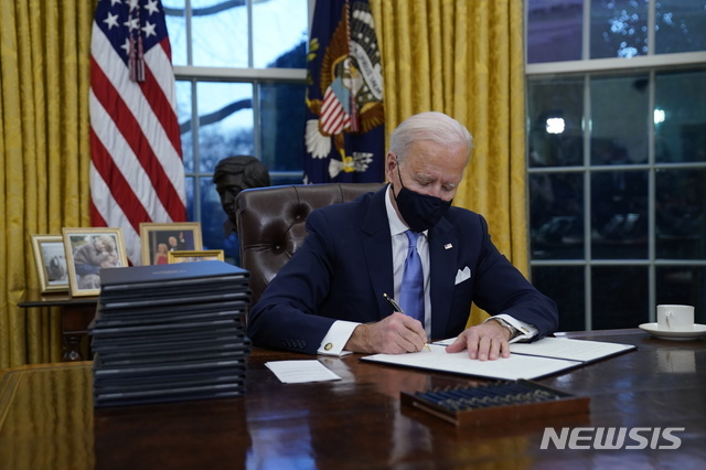 [워싱턴=AP/뉴시스]조 바이든 미국 대통령이 20일(현지시간) 백악관 오벌오피스에서 첫 행정명령에 서명하고 있다. 바이든 대통령은 이날 백악관 입성 이후 연방 부지에서 마스크 착용을 의무화하는 첫 행정명령에 서명했다.
