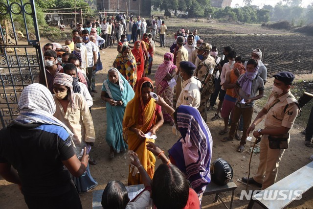 28일(현지시간) 인도 동부 비하르주 마사우디의 한 투표소 밖에서 유권자들이 투표 전 체온 검사를 받고 있다. (출처: 뉴시스)
