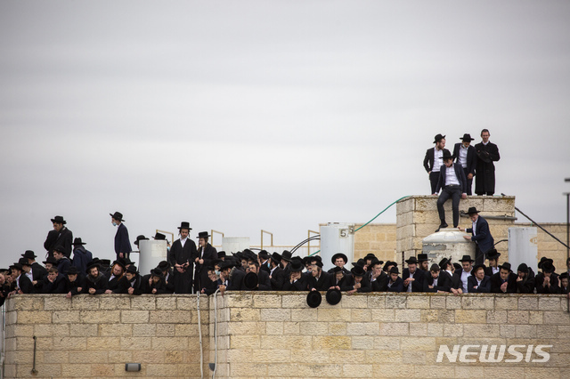 지난달 31일(현지시각) 이스라엘 예루살렘의 한 랍비 장례에 참석한 유대교인 일부가 지붕 위에 올라가 있다. 이들 대부분이 마스크를 쓰지 않은 모습이다. (출처:AP/뉴시스)