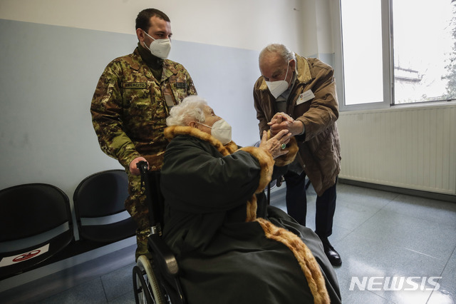 [밀라노=AP/뉴시스]18일(현지시간) 이탈리아 밀라노의 한 군 병원에서 화이자·바이오엔테크 백신 접종을 마친 102세 할머니(가운데)가 101세 할아버지와 손을 맞잡고 있다. 이탈리아의약청(AIFA)은 아스트라제네카 백신을 65세 미만 성인에 한해 사용하기로 한 바 있다.