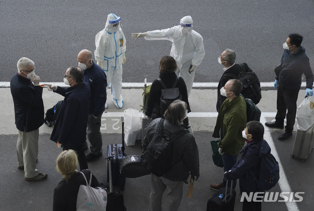 [우한=AP/뉴시스]세계보건기구(WHO) 조사단이 14일 중국 중부 후베이성 우한 공항에 도착해 입국 수속을 마치고 방호복을 입은 중국 관계자의 안내를 받고 있다.