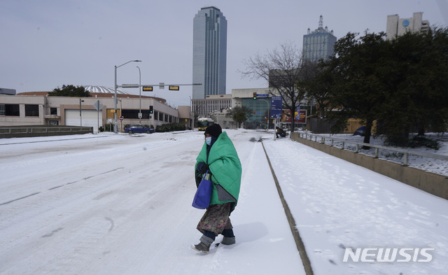 지난 16일(현지시간) 미 텍사스 댈러스 시내에서 담요를 두른 한 여성이 거리를 가로지르고 있다. (출처: 뉴시스)