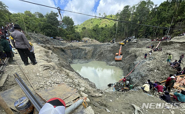 [파리기 무통=AP/뉴시스] 25일 인니 슬라웨시 섬에서 전날 밤 무너진 불법 금 채굴장에서 구조대가 물을 빼내고 있다.