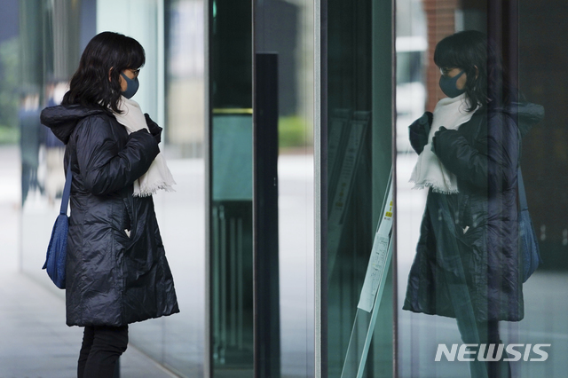 [도쿄=AP/뉴시스]26일 일본 도쿄에서 코로나19 확산 방지를 위해 마스크를 쓴 한 여성이 창문에 비친 자신의 모습을 바라보며 목도리를 매만지고 있다. 도쿄도는 26일 270명 이상의 코로나19 신규 확진자가 발생했다고 밝혔다.
