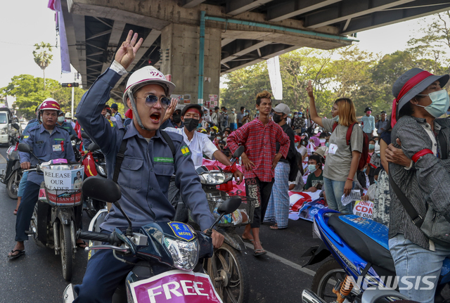 세 손가락 경례하는 미얀마 주유소 직원들[양곤=AP/뉴시스] 24일 미얀마 양곤에서 근무복을 입은 주유소 직원들이 군부 쿠데타 반대 시위에 참여해 세 손가락 경례를 하며 구호를 외치고 있다.