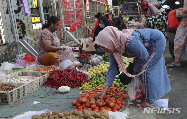 [자카르타=AP/뉴시스] 작년 4월 23일(현지시간) 인도네시아 자카르타의 한 길거리 시장에서 한 여성이 식료품을 사고 있다.