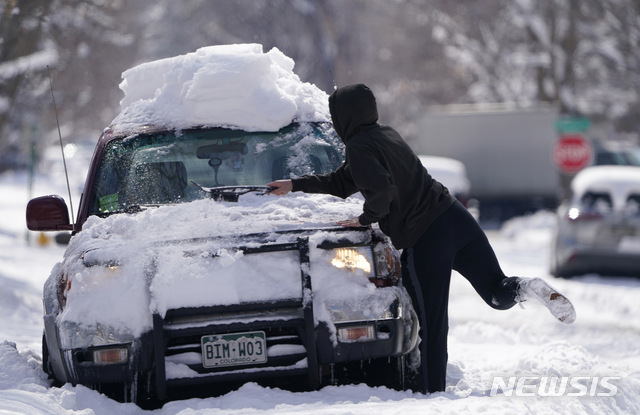 덴버=AP/뉴시스]25일(현지시간) 미 콜로라도주 덴버를 휩쓴 겨울 폭풍으로 30㎝ 이상 눈이 내린 가운데 한 운전자가 자신의 차에 쌓인 눈을 치우고 있다.