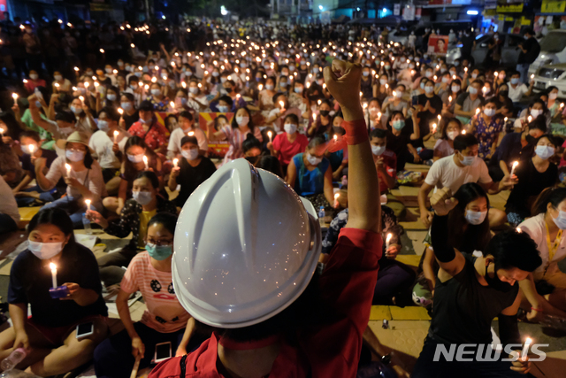 반 군부 쿠데타 촛불집회 벌이는 미얀마 시위대[양곤=AP/뉴시스] 14일 미얀마 양곤에서 열린 군부 쿠데타 반대 촛불집회가 열려 한 시위 참가자가 군중 앞에서 주먹을 들고 있다. 미얀마 군정이 양곤의 두 곳에 계엄령을 선포하고 유혈 진압을 이어가면서 이날만 최소 38명이 숨졌다고 외신들이 보도했다.