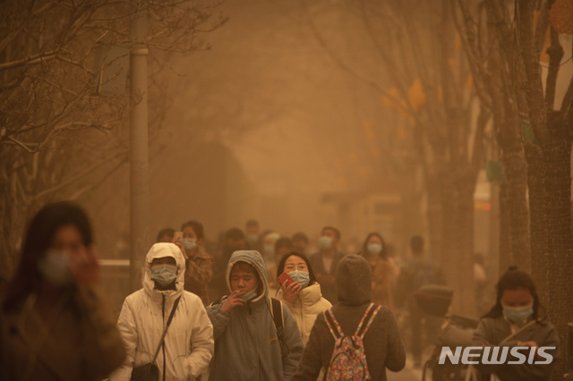 [베이징=AP/뉴시스] 15일 중국 베이징에 심각한 황사가 발생한 가운데 거리에 출근하는 시민들이 걸어가고 있다.