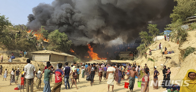 [콕스바자르=AP/뉴시스]22일(현지시간) 방글라데시 남부 콕스바자르의 바루칼리에 있는 로힝야 난민촌에서 화재가 발생해 로힝야 난민들이 연기가 피어오르는 모습을 지켜보고 있다. 현지 관계자와 목격자들은 이 불로 수백 채의 가옥이 소실되고 수천 명의 이재민이 발생했다고 밝혔다.