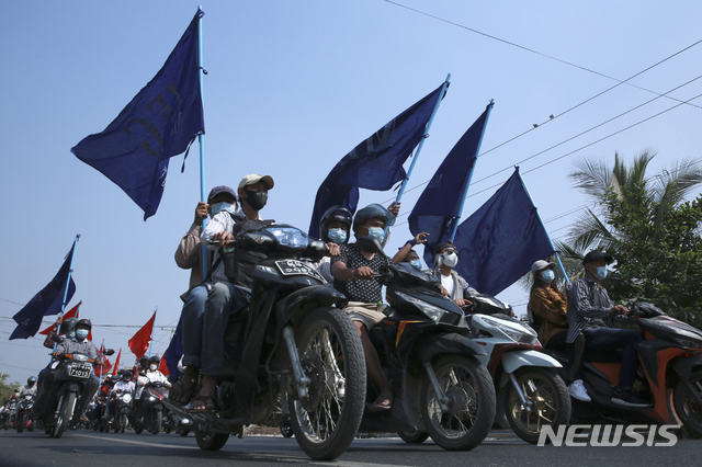 [만달레이=AP/뉴시스] 25일 미얀마 만달레이에서 깃발을 든 쿠데타 반대 시위대가 오토바이를 몰고 행진하고 있다. 미얀마 시위대는 24일 집 안에 머물며 상점 문을 닫는 등 '침묵시위'를 벌인 지 하루 만에 다시 거리로 나왔다.