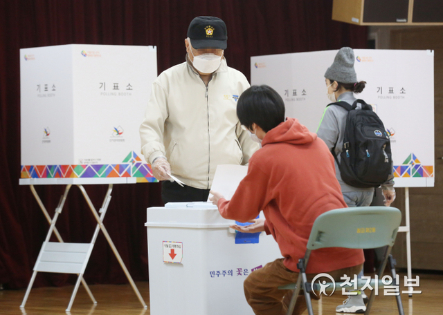 4.7 재보궐선거일인 7일 오전 서울 용산구 청파도서관에 마련된 청파동 제1투표소에서 한 유권자가 투표용지를 투표함에 넣고 있다. ⓒ천지일보 2021.4.7