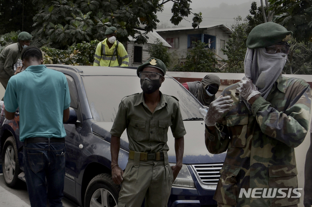 10일(현지시간) 카리브해 동부 세인트루이스섬에 있는 킹스타운에서 군인들과 주민들이 환산재로 뒤덮인 차량 옆에 서 있다. (출처: 뉴시스)
