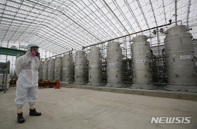 일본 후쿠시마현 오쿠마에 있는 원전 오염수 처리시설에서 2014년 11월 12일 한 직원이 방사성 물질 보호복을 입고 서 있다. (출처: 뉴시스)