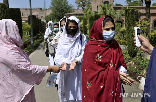 [페샤와르=AP/뉴시스] 19일(현지시간) 파키스탄 페샤와르의 한 학교에서 교사들이 코로나19 확산 방지를 위해 학생들의 손에 소독제를 뿌리고 체온을 점검하고 있다. 파키스탄은 코로나19로 감염자와 사망자가 꾸준히 늘고 있음에도 9~12학년을 대상으로 학교를 재개교 했다. 2021.04.19.