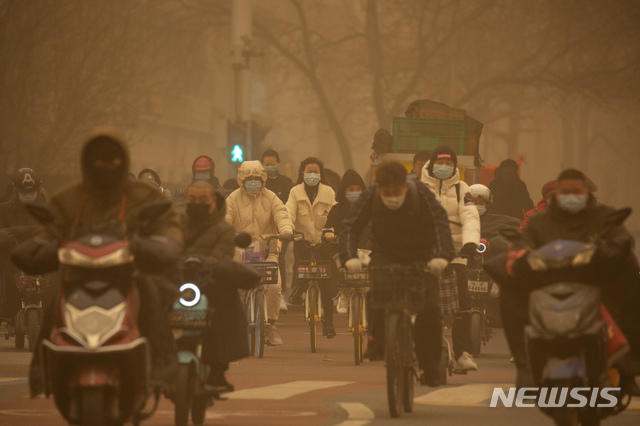 [베이징=AP/뉴시스] 지난 3월 15일 중국 베이징이 공기 오염과 황사로 온통 뿌연 가운데 마스크를 쓴 출근길 시민들이 자전거 등을 타고 교차로를 지나고 있다. 중국 기상대는 베이징과 북부 지역에서 발생한 심각한 황사로 올해 첫 황사 경보를 발령했다.