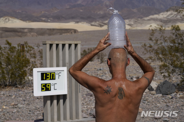 2020년 8월 17일 미국 캘리포니아 데스밸리 국립공원에서 한 남성이 얼음 물병을 머리에 이고 더위를 식히고 있다. 남성 앞으로 보이는 온도계는 54.4도를 기록하며 이 지역에서 최고 온도를 기록했다. (출처: 뉴시스)