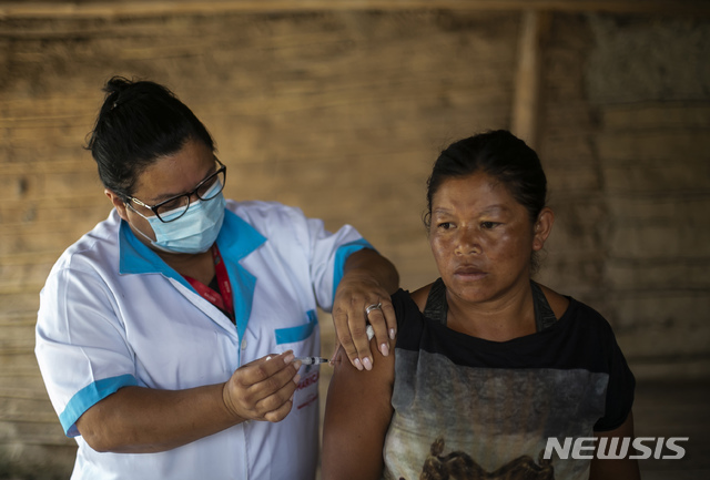 [리우데자네이루=AP/뉴시스] 2월 25일(현지시간) 브라질 리우데자네이루주 마리카에 있는 마타 베르드 보니타 마을을 방문한 보건 종사자가 한 과라니 원주민 여성에게 중국의 시노백 백신을 접종하고 있다.