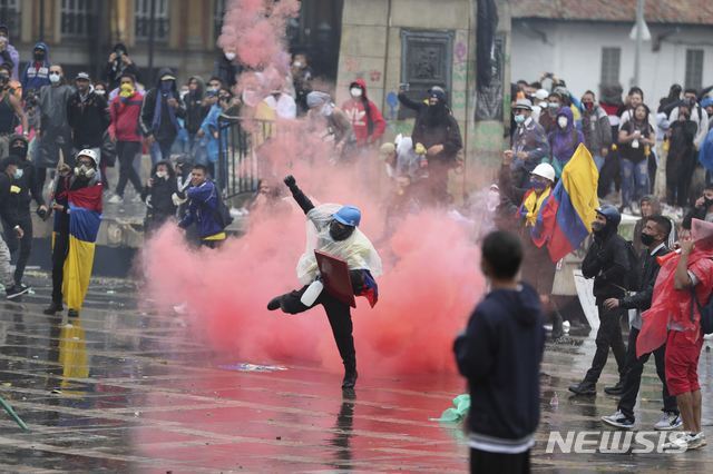 [보고타=AP/뉴시스]5일(현지시간) 콜롬비아 수도 보고타에서 반정부 시위대가 경찰과 충돌하던 중 한 시위 참가자가 최루탄을 경찰에 되던지고 있다. 정부의 세제 개편안에 대한 반대로 시작된 이번 시위는 지난 2일 이반 듀크 대통령의 개편안 철회 결정에도 끝나지 않고 계속 이어지고 있다.