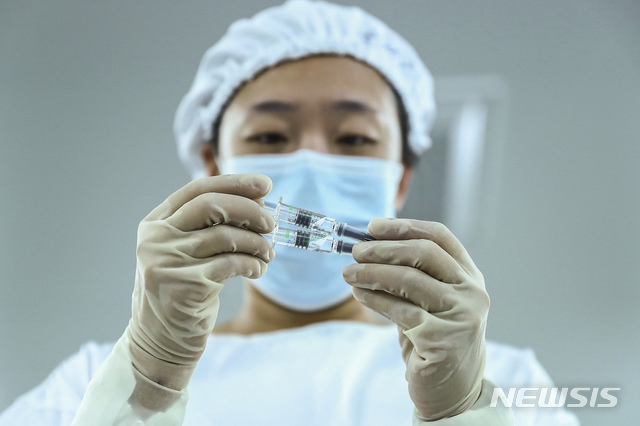 [베이징=AP/뉴시스] 중국 시노팜 베이징 공장에서 한 직원이 코로나19 백신을 살펴보고 있다. 사진은 기사 내용과 무관. 2020.12.31