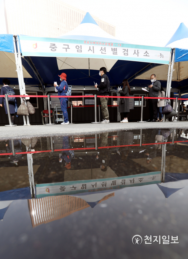 [천지일보=남승우 기자] 신종 코로나바이러스 감염증(코로나19) 신규 확진자가 525명으로 집계된 7일 오후 서울역 광장에 마련된 임시 선별검사소에서 시민들이 코로나19 검사를 받기 위해 기다리는 모습이 고인 빗물에 비치고 있다. ⓒ천지일보 2021.5.7