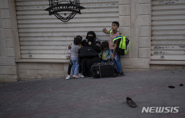 12일(현지시간) 이스라엘군이 가자지구를 공습하자 한 팔레스타인 가족이 건물에서 대피해 길가에 앉아 있다. (출처: 뉴시스)