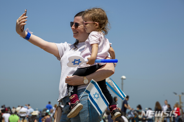 지난 15일 이스라엘 텔아비브에서 열린 독립기념일 기념행사에서 한 여성이 아이와 이스라엘 국기를 들고 미소를 짓고 있다. 세계 코로나19 백신 접종률 1위 이스라엘에서는 야외 마스크 의무 착용을 해제하는 등 일상 회복을 추진하고 있다. (출처: 뉴시스)