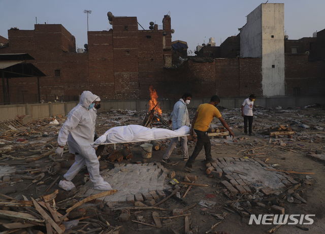 [벵갈루루=AP/뉴시스]12일(현지시간) 인도 벵갈루루 외곽 공공 화장터에서 유가족과 자원봉사자들이 코로나19로 사망한 사람의 시신을 화장하기 위해 옮기고 있다.