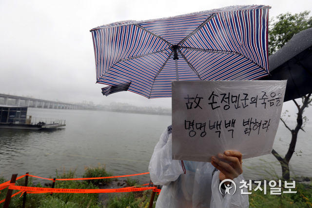 [천지일보=남승우 기자] 16일 오후 서울 서초구 반포한강공원 수상택시 승강장 인근에서 열린 고 손정민 추모 집회에서 한 시민이 우산을 쓴 채 진상규명을 촉구하는 피켓을 들고 있다. ⓒ천지일보 2021.5.16