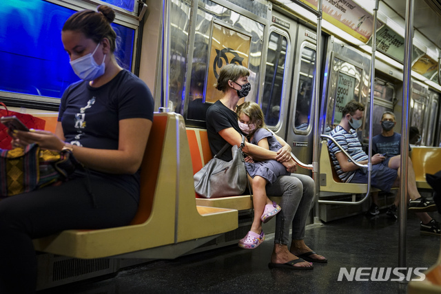 뉴욕의 지하철 안에서 마스크를 쓴 한 여자아이가 엄마의 무릎에 앉아 쉬고 있는 모습. (출처: 뉴시스)