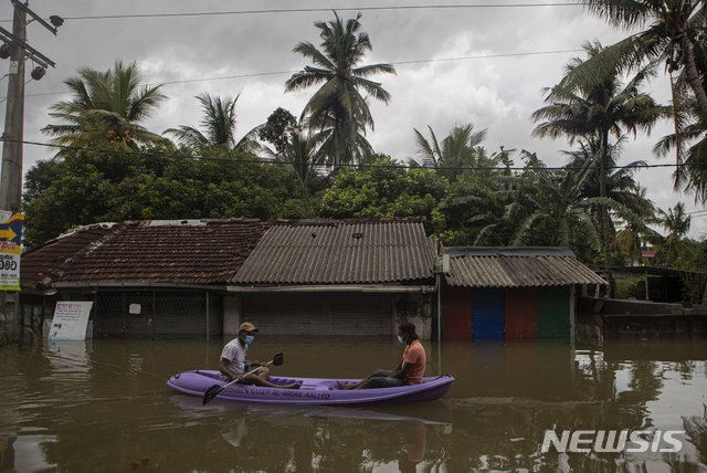 5일(현지시간) 스리랑카 콜롬보 외곽의 말와 나에서 폭우가 발생한 가운데 스리랑카인들이 침수 된 거리를 뗏목을 타고 이동하고 있다. 이번 폭우로 촉발 된 돌발 홍수와 산사태로 최소 4명이 사망, 7명이 실종 됐다. (출처: 뉴시스)