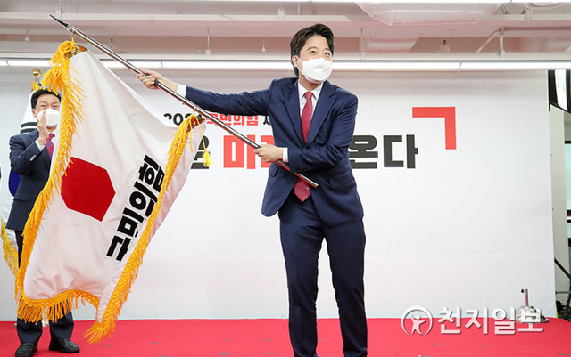 [천지일보=박준성 기자] 국민의힘 이준석 신임 대표가 11일 서울 영등포구 국민의힘 당사에서 열린 전당대회에서 당기를 흔들고 있다. ‘30대·0선’의 이 대표는 역대급 전당대회 흥행을 주도한 끝에 헌정사상 최초의 30대 보수정당 대표에 올랐다. (제공: 국민의힘) ⓒ천지일보 2021.6.11