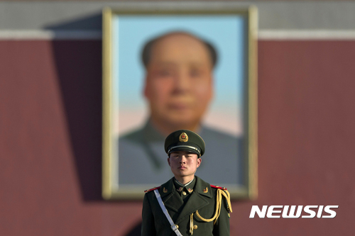 【베이징=AP/뉴시스】중국 베이징 톈안먼 광장에서 13일 한 경찰이 마오쩌둥의 대형 초상화를 뒤로 하고 서있다.
