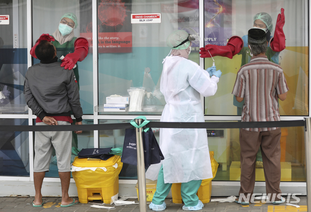 [자카르타=AP/뉴시스]14일(현지시간) 인도네시아 수도 자카르타의 한 워크스루 코로나19 검사장에서 의료진이 사람들의 검체를 채취하고 있다.