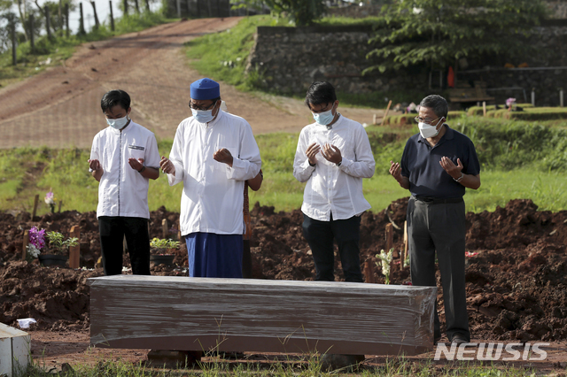 21일 인도네시아 자카르타 외곽 귤랑의 공립묘지에서 이슬람 성직자가 코로나19로 사망한 한 남성을 매장하는 동안 유족들과 기도를 하고 있다. 인도네시아는 최근 델타 변이로 확진자 수가 크게 늘었다. (출처: 뉴시스)