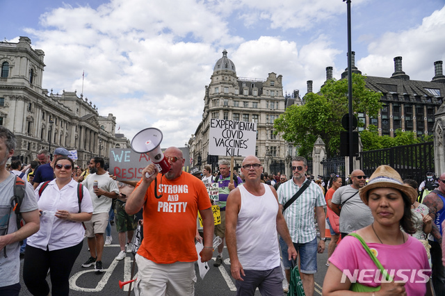[런던=AP/뉴시스]14일(현지시간) 영국 런던의 웨스트민스터 궁 앞에서 코로나19 봉쇄 해제 연기에 대한 항의 시위가 열려 시위대가 구호를 외치며 행진하고 있다. 보리스 존슨 영국 총리는 코로나19 변이 바이러스 '델타'가 확산하면서 애초 이달 21일 해제하려던 봉쇄조치를 7월 19일로 4주간 연기한다고 밝혔다.