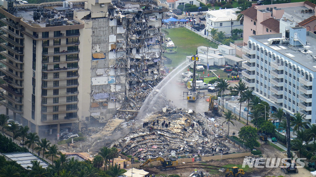미국 플로리다주 마이애미데이드카운티 서프사이드에 있는 12층 콘도형 아파트가 붕괴된 후 25일(현지시간) 수색 작업을 하는 가운데 잔해 더미에서 화재가 발생해 진화하고 있다. 이번 사고로 최소 5명이 사망했고, 156명이 실종됐다. (출처: 뉴시스)