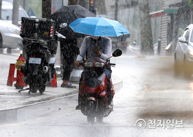 [천지일보=남승우 기자] 소나기가 내린 23일 오후 서울 중구의 한 거리에서 라이더가 우산을 들고 오토바이를 운전하고 있다. ⓒ천지일보 2021.6.23