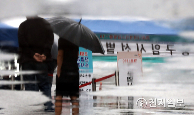 [천지일보=남승우 기자] 비가 내린 25일 오전 서울역 광장에 마련된 임시 선별검사소에서 우산을 쓴 시민들이 신종 코로나바이러스 감염증(코로나19) 검사를 받기 위해 기다리는 모습이 고인 빗물에 비치고 있다. 이날 코로나19 신규 확진자는 516명으로 집계됐다. ⓒ천지일보 2021.5.25